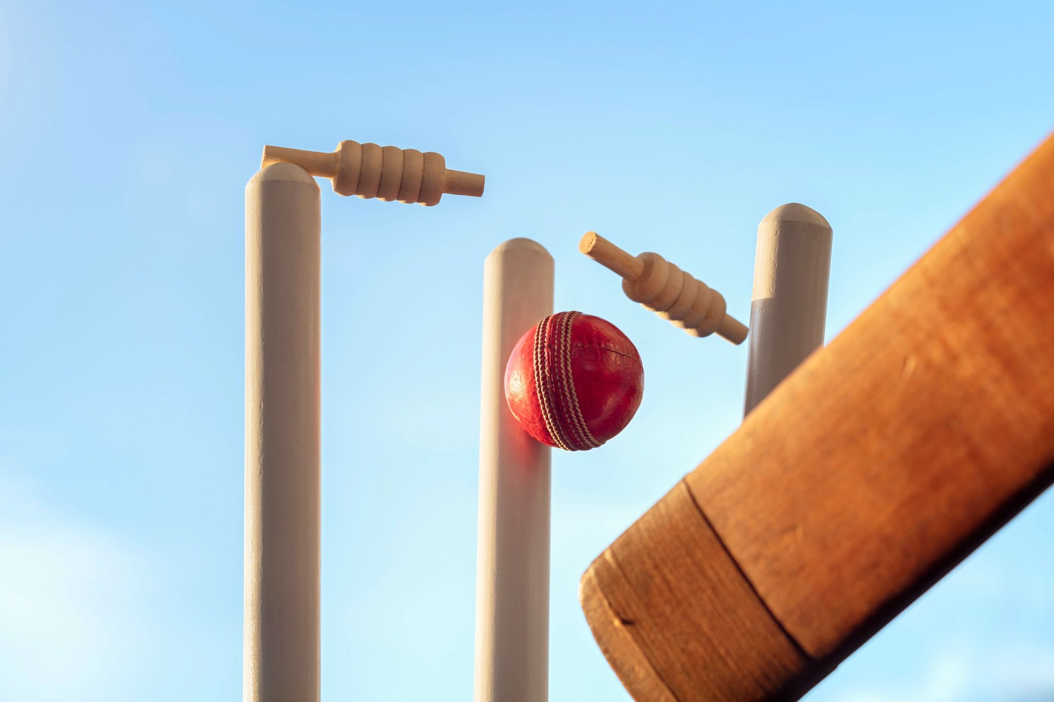 Cricket bat and cricket ball hitting wicket stumps
